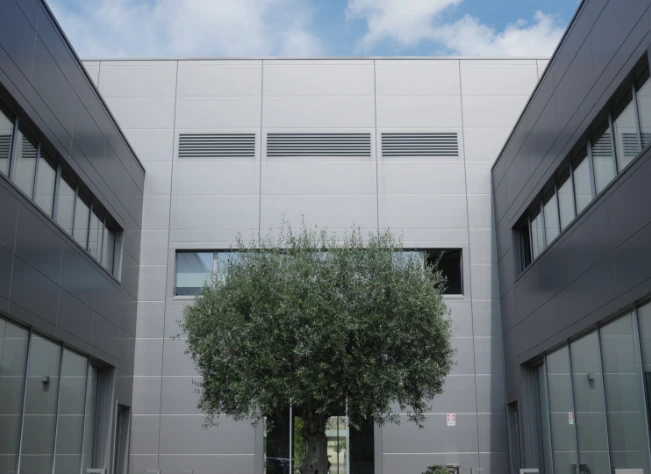 Facciata esterna della sede aziendale Cariaggi, caratterizzata da un design moderno con un albero al centro, simbolo di sostenibilità e tradizione.