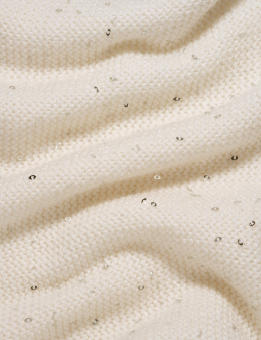 Tessuto in cashmere pettinato decorato con paillettes delicate, che aggiungono un tocco di eleganza scintillante alla trama morbida e raffinata.