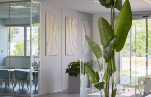 Spazi interni della sede Cariaggi, con design moderno, ampie vetrate e piante che creano un ambiente accogliente e sostenibile.