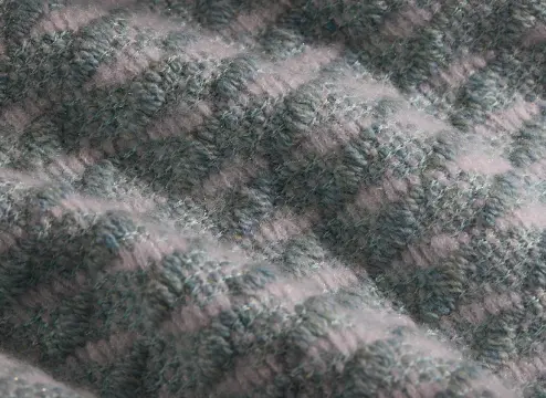 Dettaglio di tessuto cashmere con una lavorazione melange, che alterna tonalità di grigio e verde per un effetto unico.