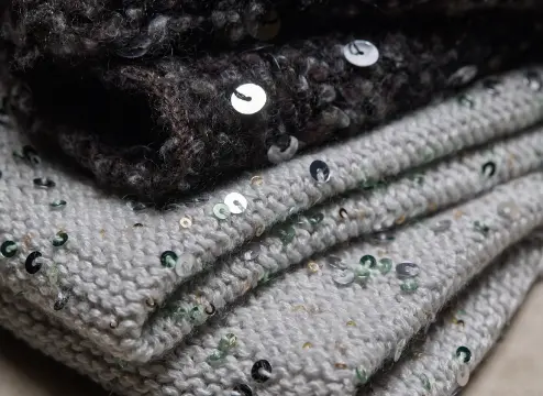 Strati di tessuti decorati con paillettes lucenti su tonalità di grigio e nero, perfetti per un look glamour sofisticato.