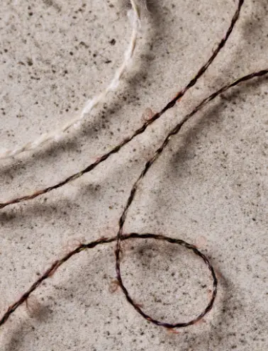 Primo piano di un filato naturale in tonalità terrose, intrecciato con una texture liscia e raffinata.
