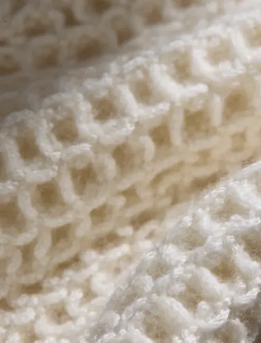 Struttura in cashmere con motivo a nido d’ape, che combina eleganza e morbidezza in un design classico e versatile.