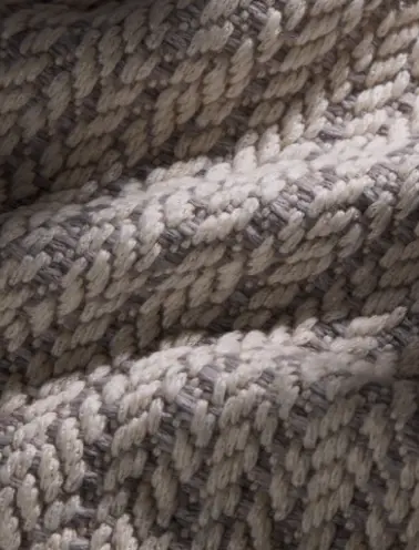Dettaglio di tessuti intrecciati con filati cashmere, in tonalità naturali che esaltano la lavorazione artigianale.